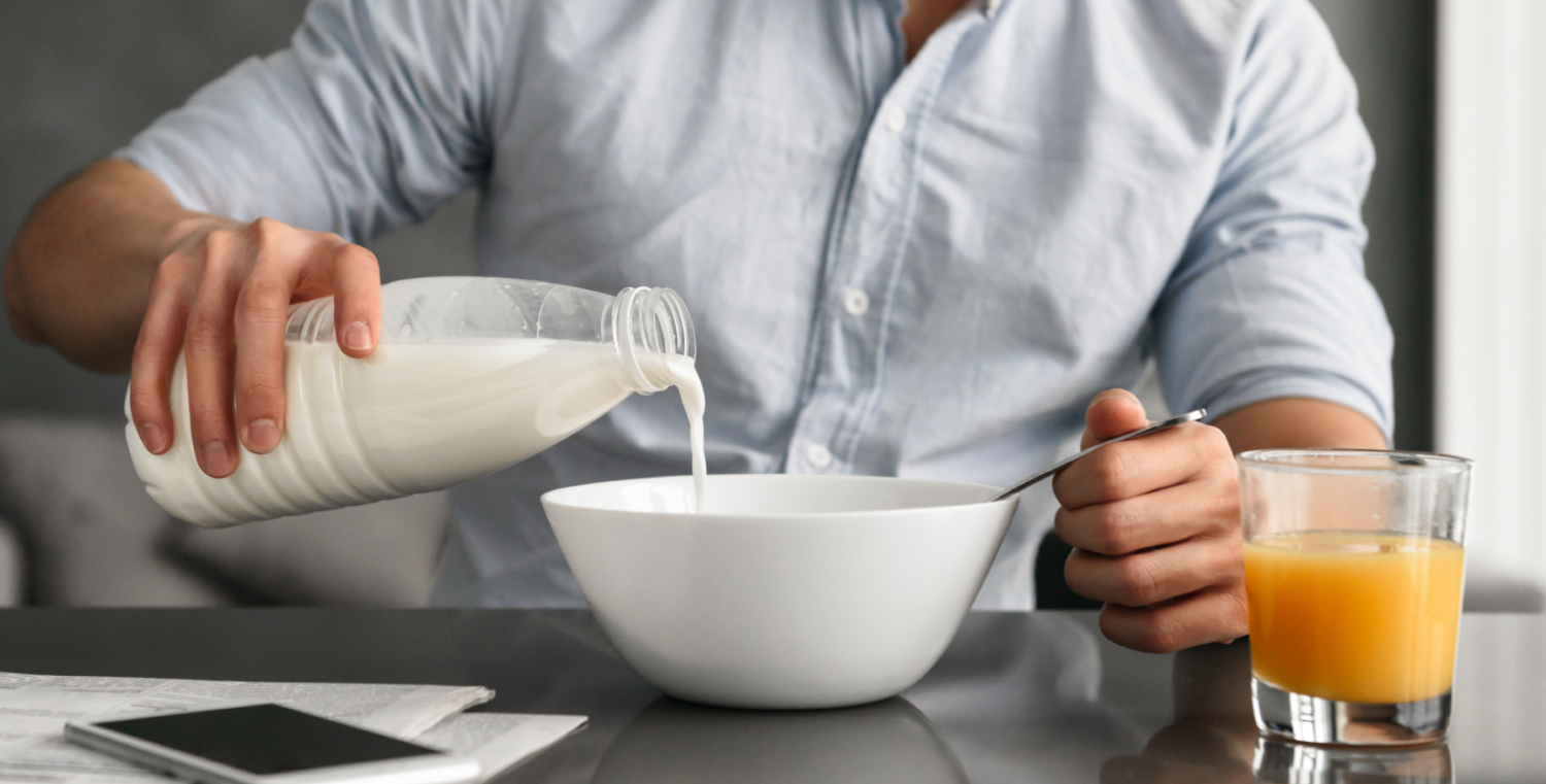 Eine Person schüttet sich Milch in die Frühstücksschüssel.