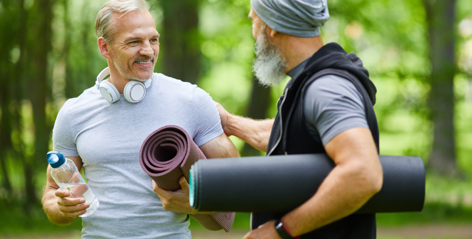 Zwei Männer mit Yogamatten vor dem Sport, der das Herz stärken wird.