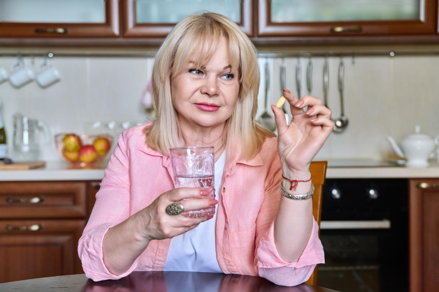 Eine Frau mit Eisenmangel nimmt ein Eisenpräparat mit Wasser ein.