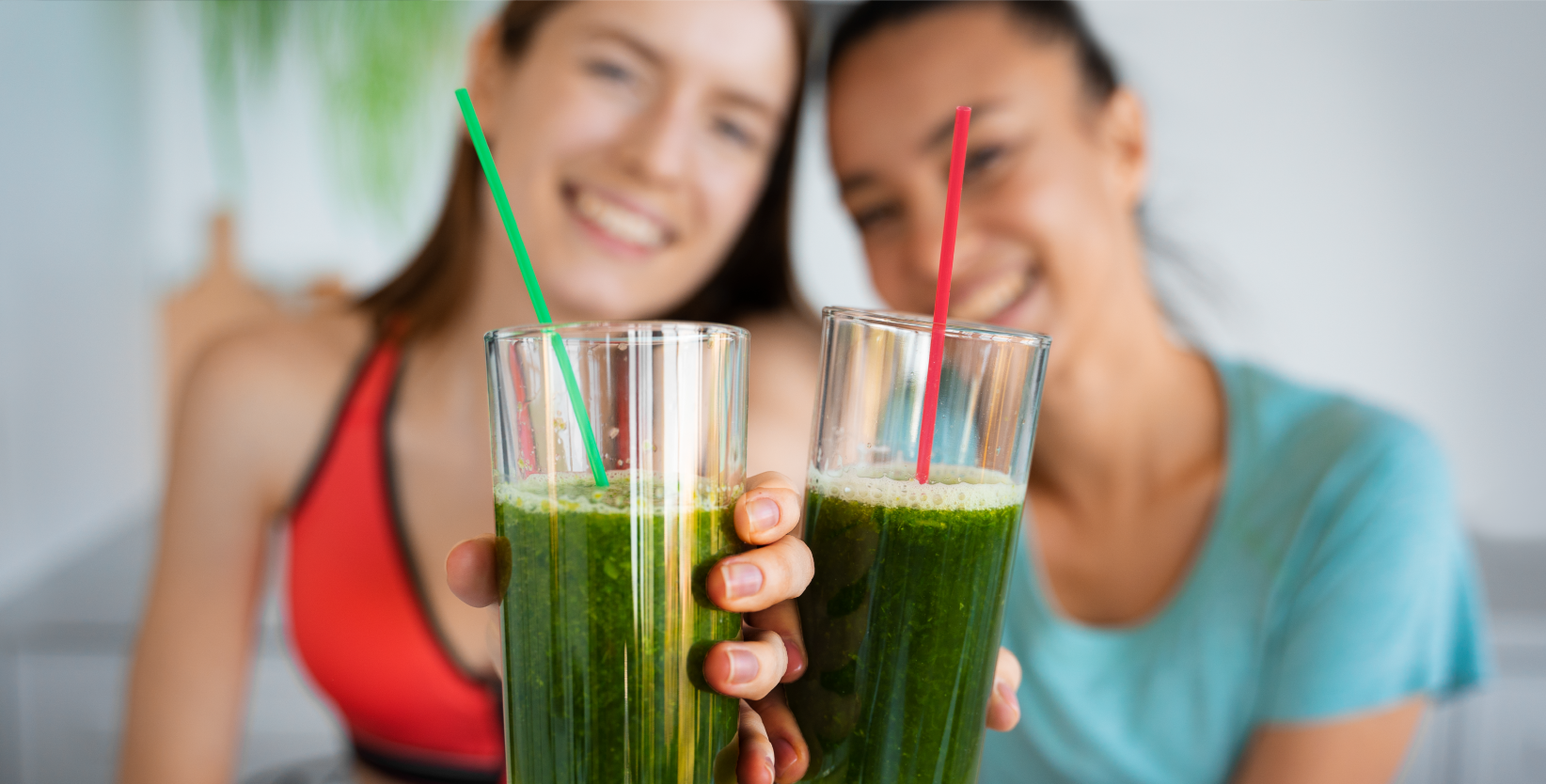 Zwei Frauen stoßen mit Säften auf das Leber-Detox an.