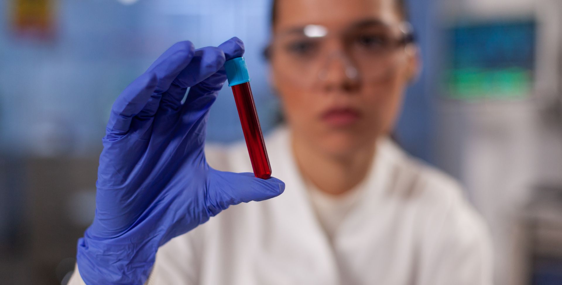 Eine Labormitarbeiterin hält ein Röhrchen mit Blut, um seine Bestandteile zu analysieren.