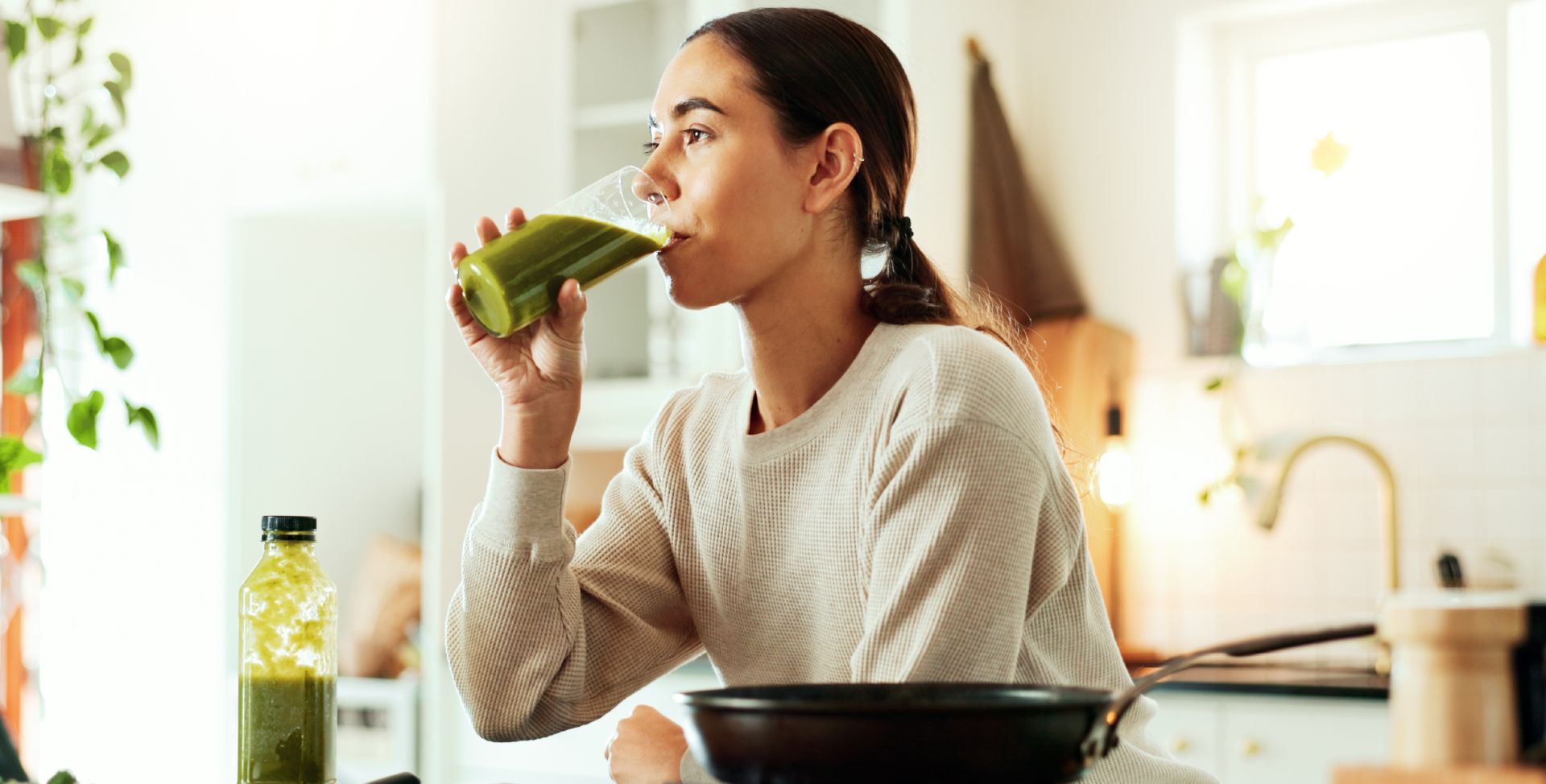 Eine Frau trinkt einen grünen Smoothie mit natürlichem Magnesium.