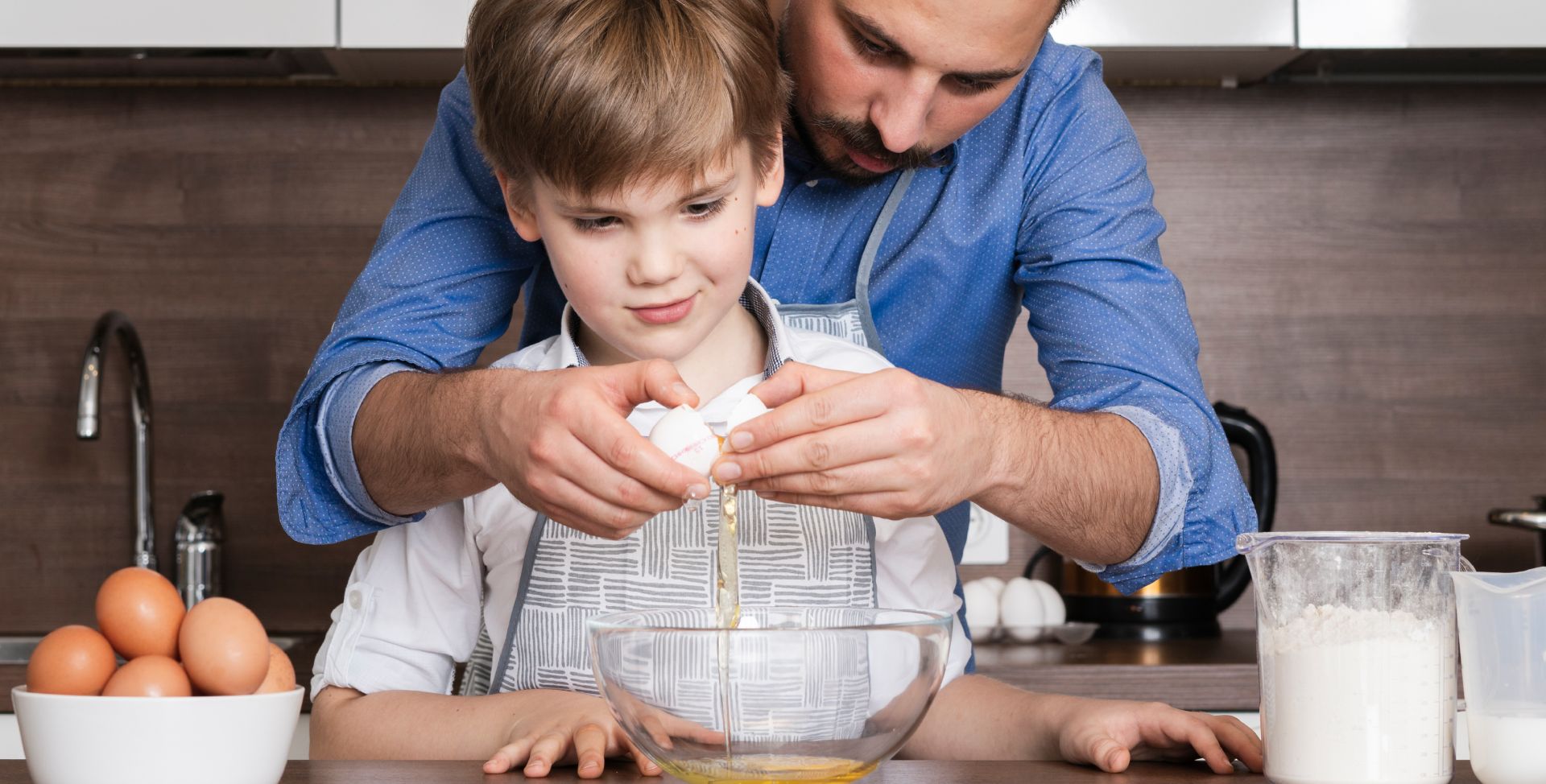 Ein Vater und ein Sohn kochen mit Eiern und Milch, die natürliches Vitamin A enthalten.