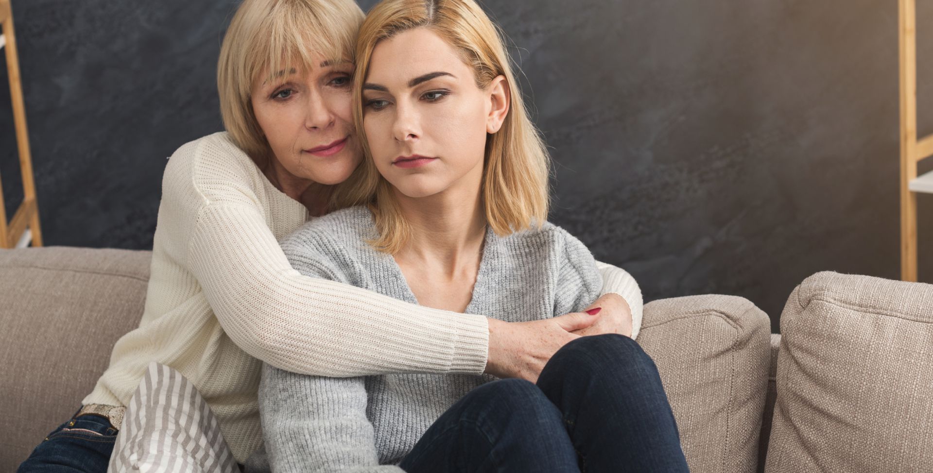 Eine ältere Dame umarmt eine traurige Frau. Depressionen sind vererbbar.