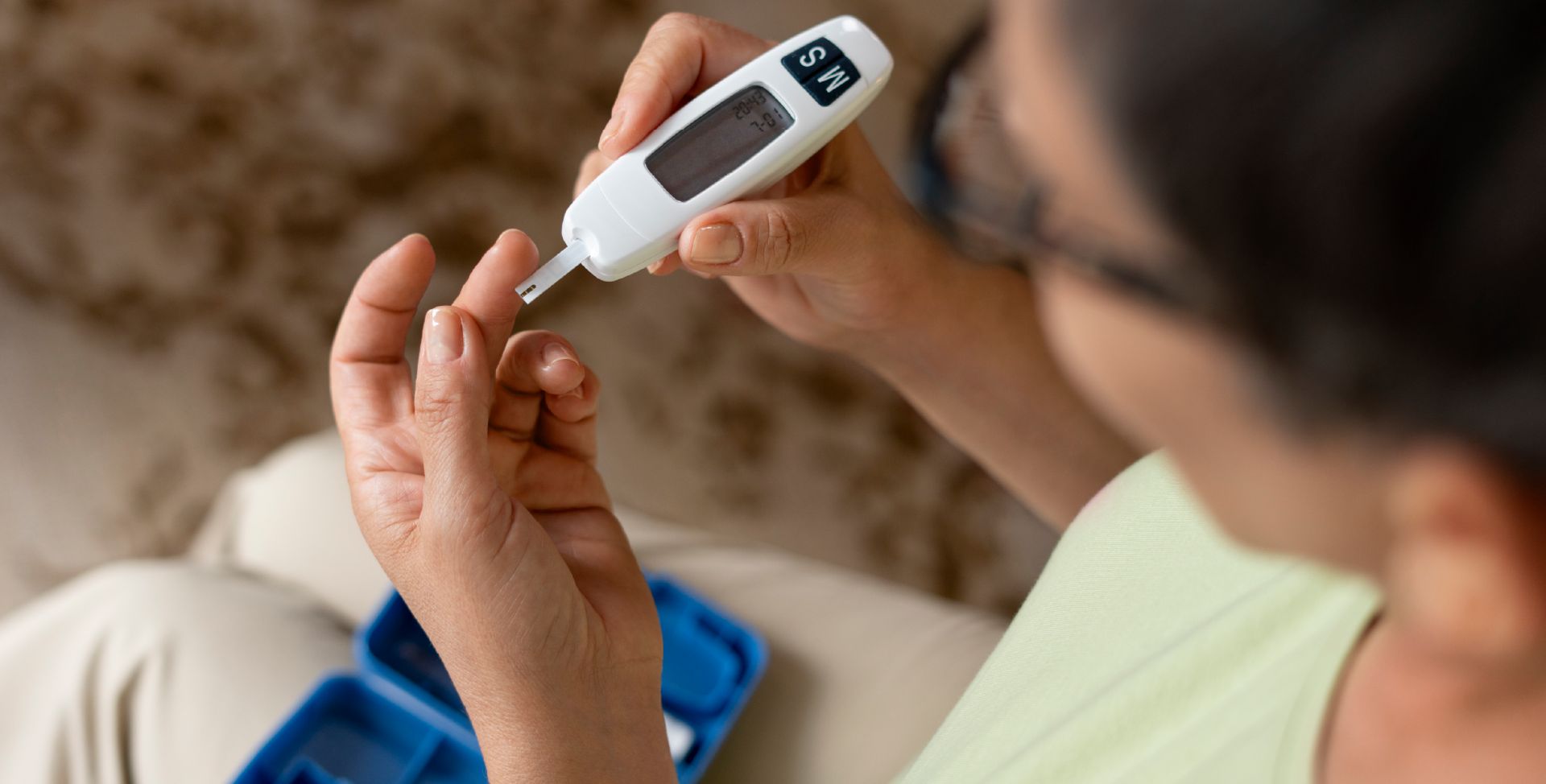 Eine Frau misst ihren Blutzucker zur Kontrolle von Diabetes Typ 2.
