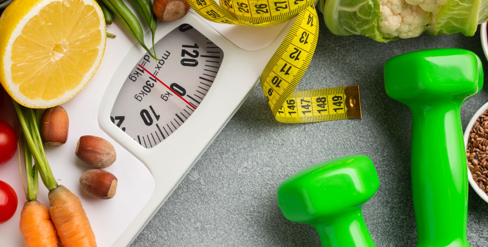 Eine Waage, halbe Zitrone, Karotten, ein Maßband und Hanteln stehen für Nutrigenetik, die personalisierte Ernährung ermöglicht.