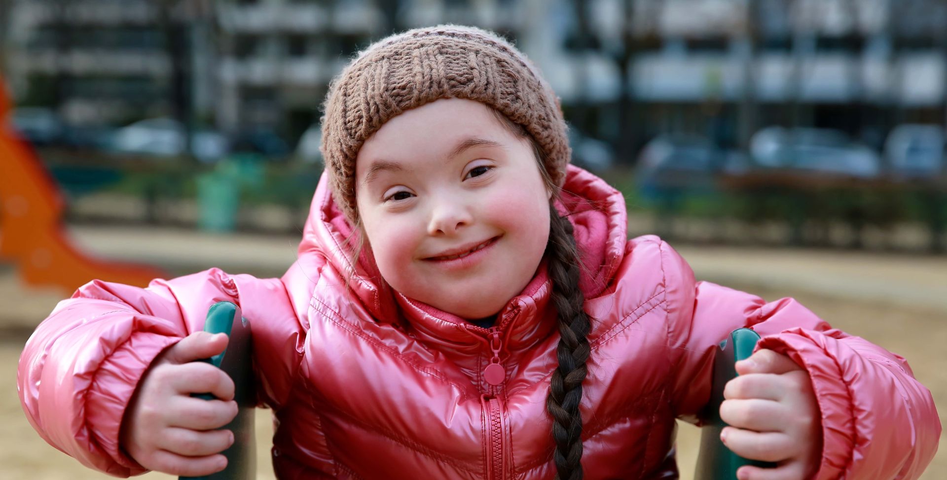 Ein Mädchen mit Down-Syndrom lächelt in die Kamera.