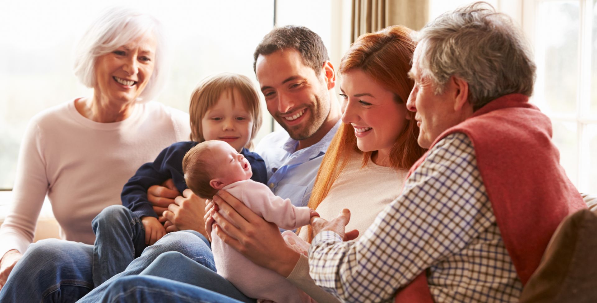 Eine Familiesitzt um ein Neugeborenes herum, das mithilfe einer genetischen Untersuchung gesund bleibt.