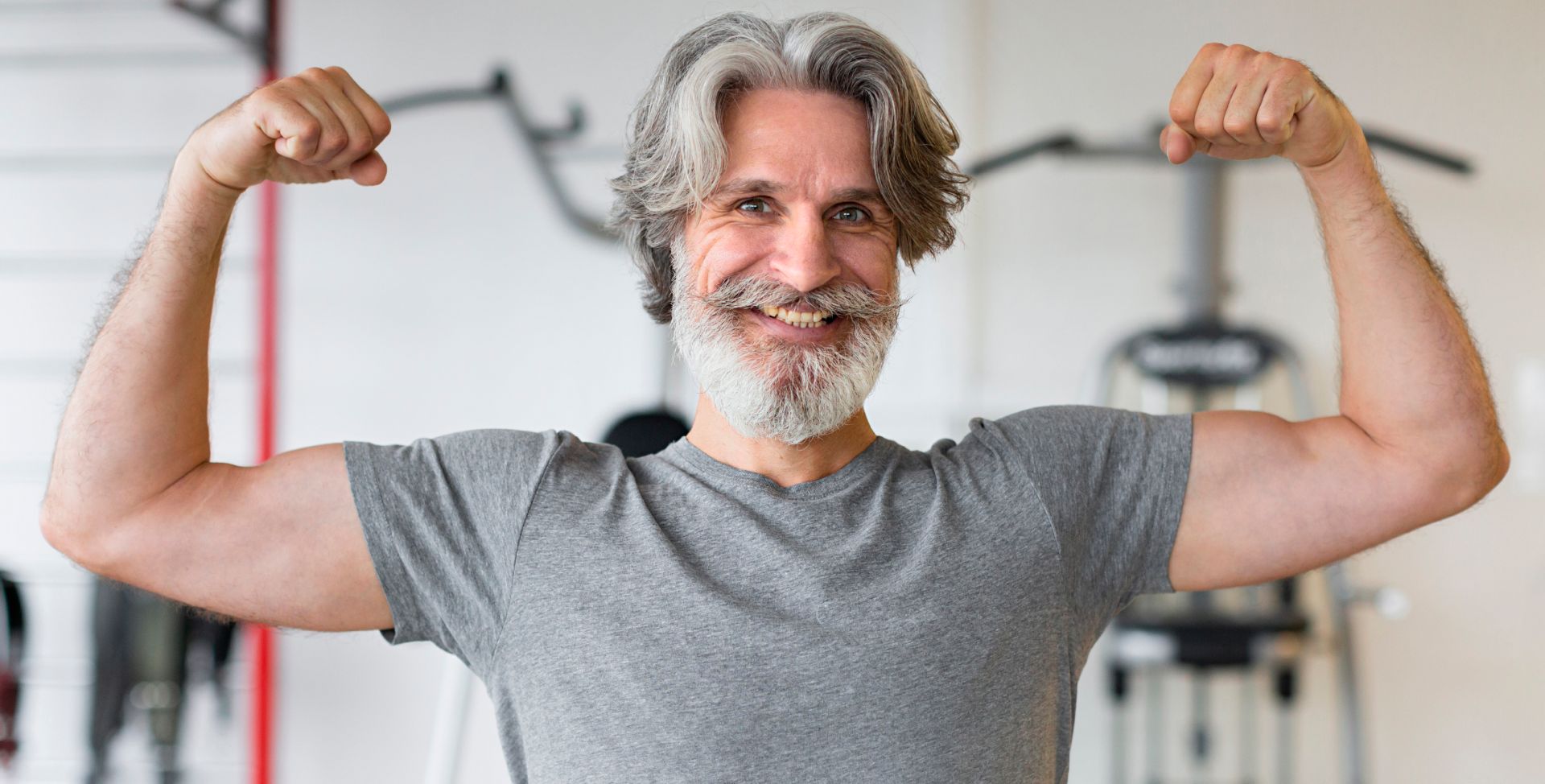 Ein älterer Mann zeigt seine Muskeln, für die das Hormon Testosteron wichtig sind.
