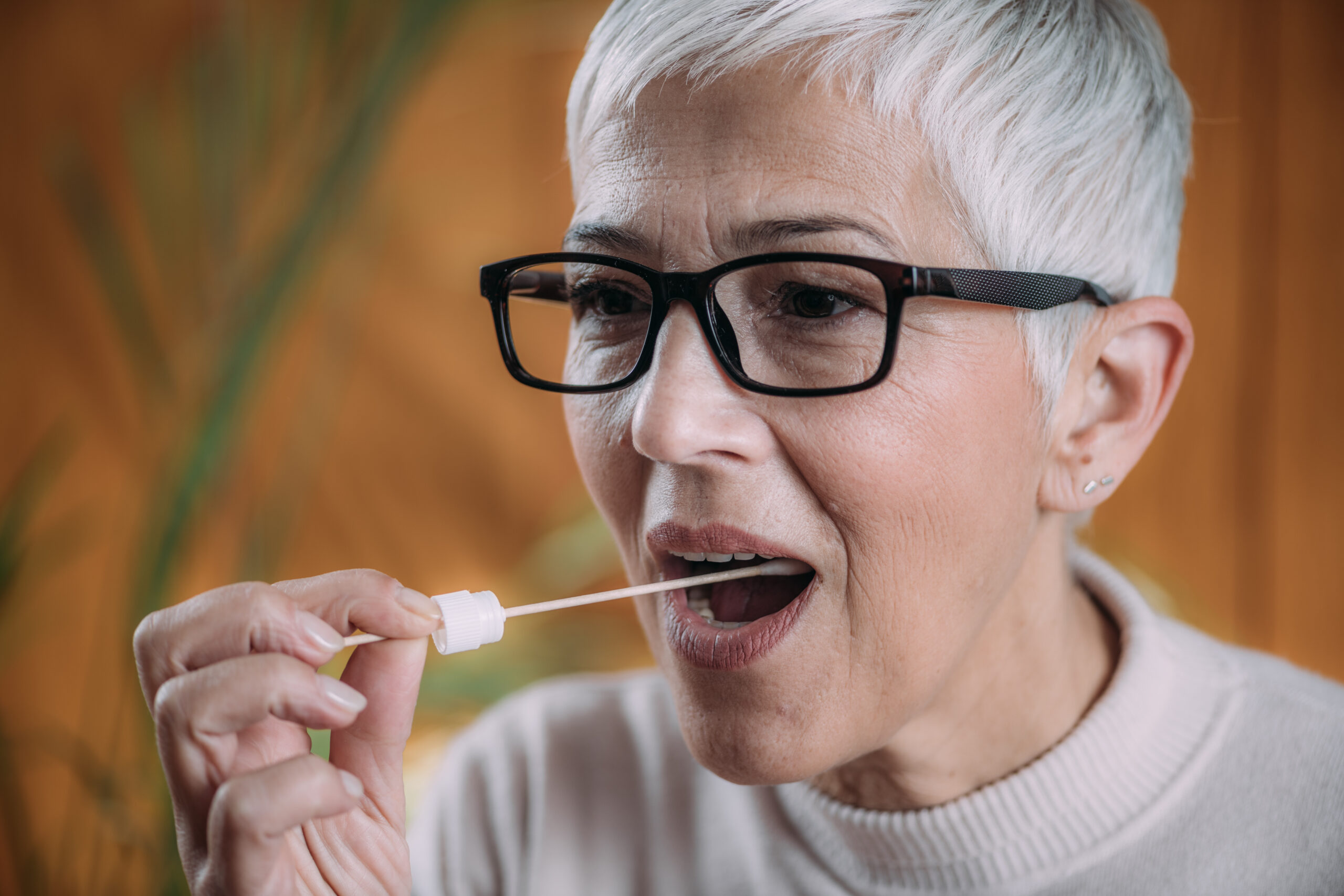 Eine Frau nimmt einen Wangenabstrich für einen DNA-Test mithilfe des Abstrichtupfers.