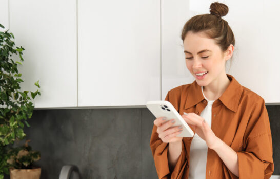 Eine junge Frau sieht Ihre Ergebnisse auf Ihrem Smartphone.