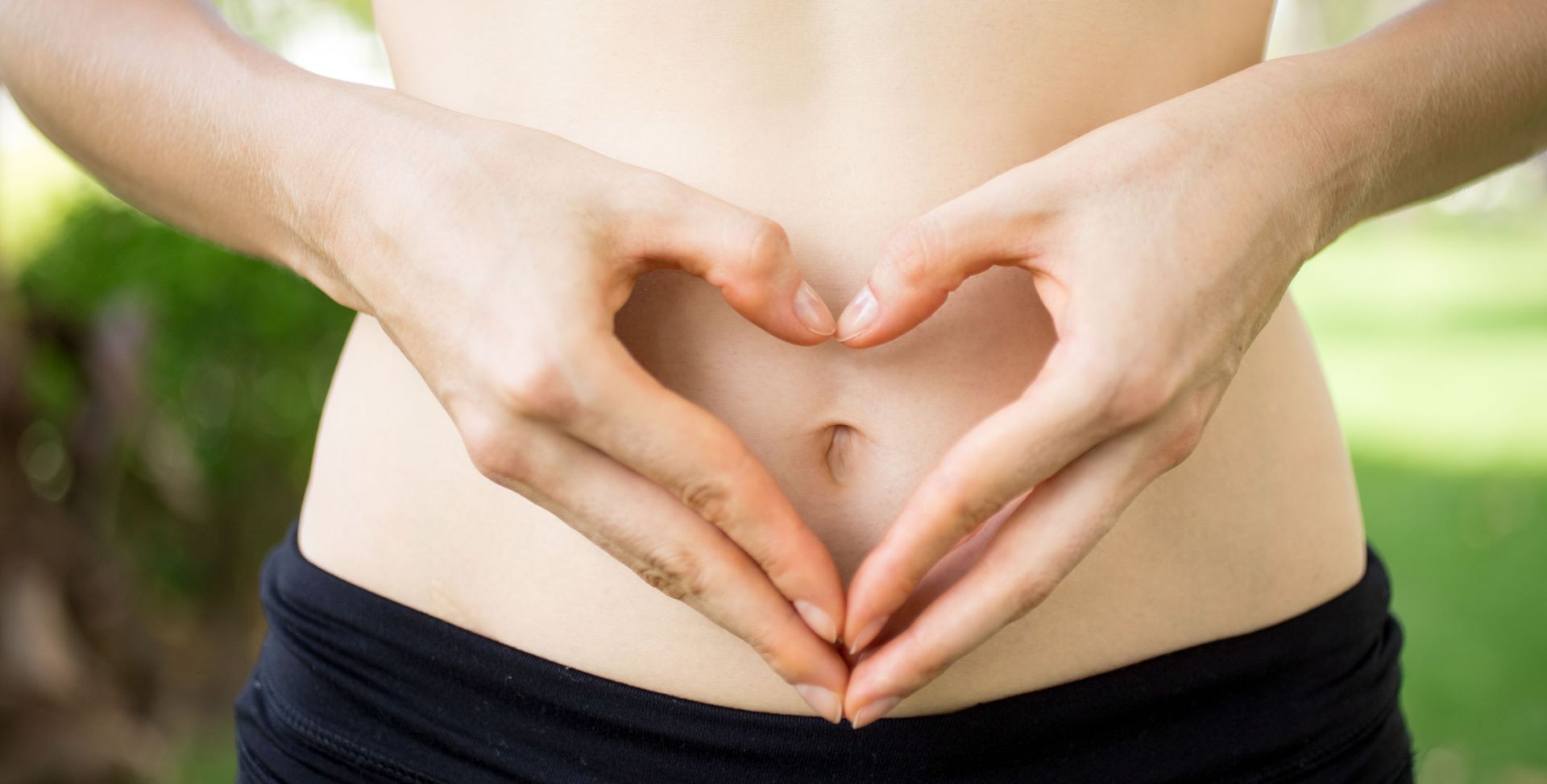 Eine Person bildet mit den Händen ein Herz über dem Bauchnabel. Sinnbild für Tipps, um die Darmgesundheit zu fördern.