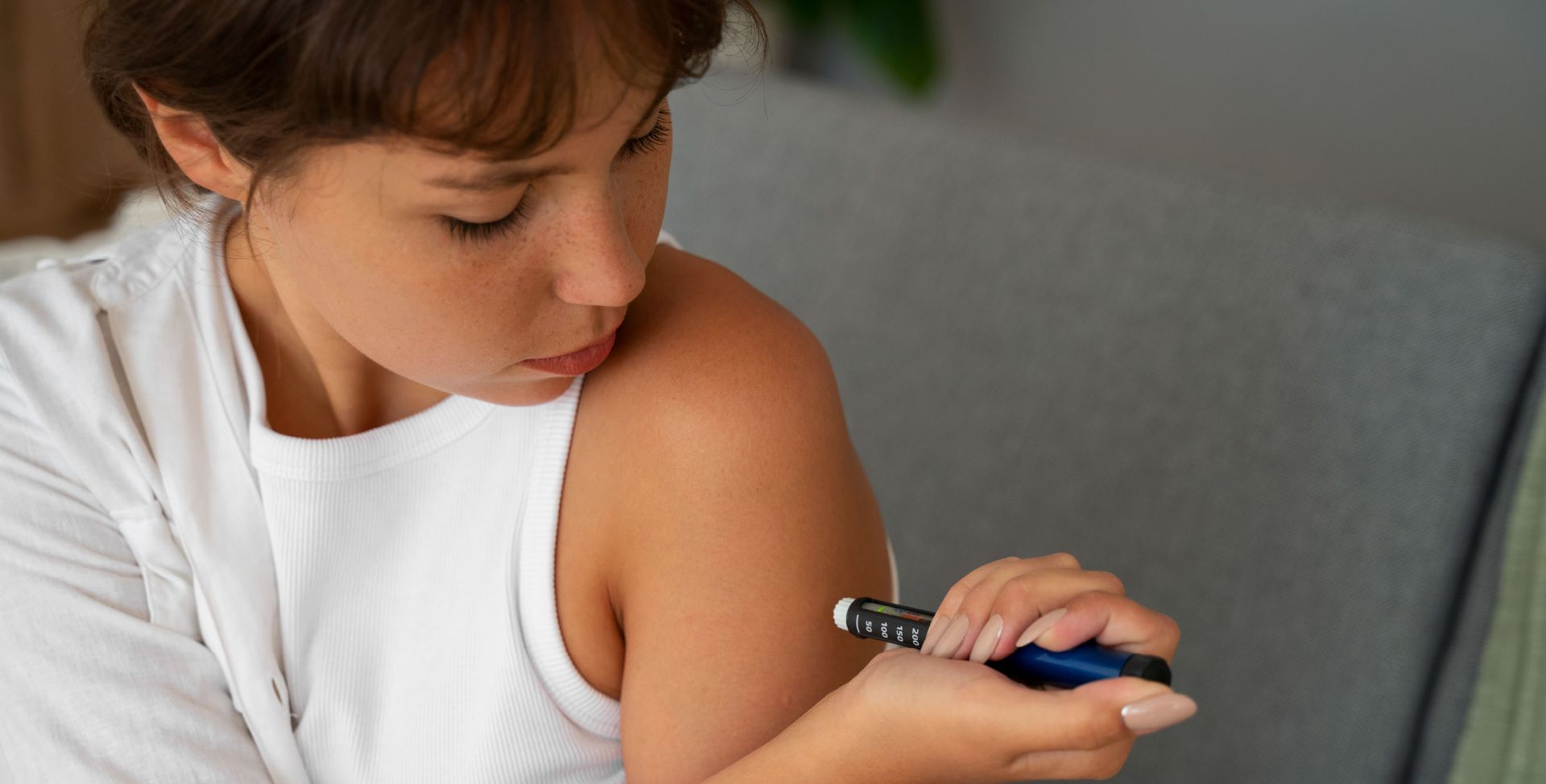 Eine Frau spritzt mit einem Pen das Hormon Insulin in ihren Arm.