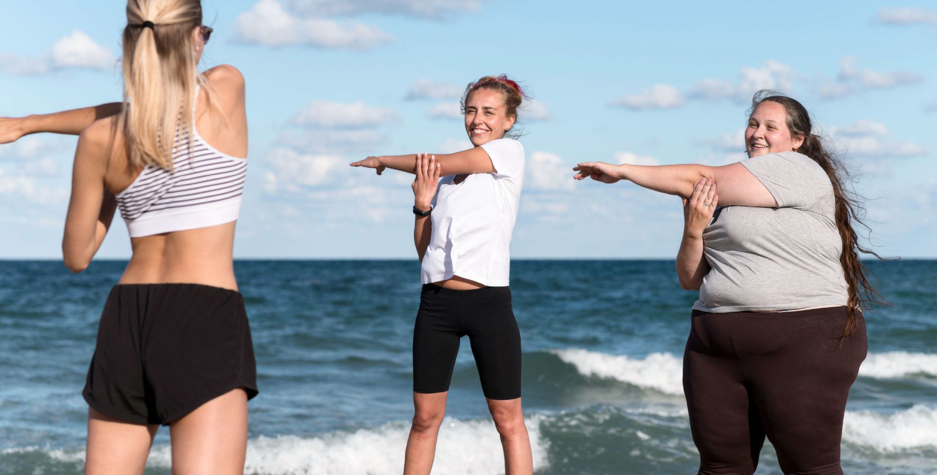 Frauen dehnen sich am Strand, um den Stoffwechsel anzukurbeln.