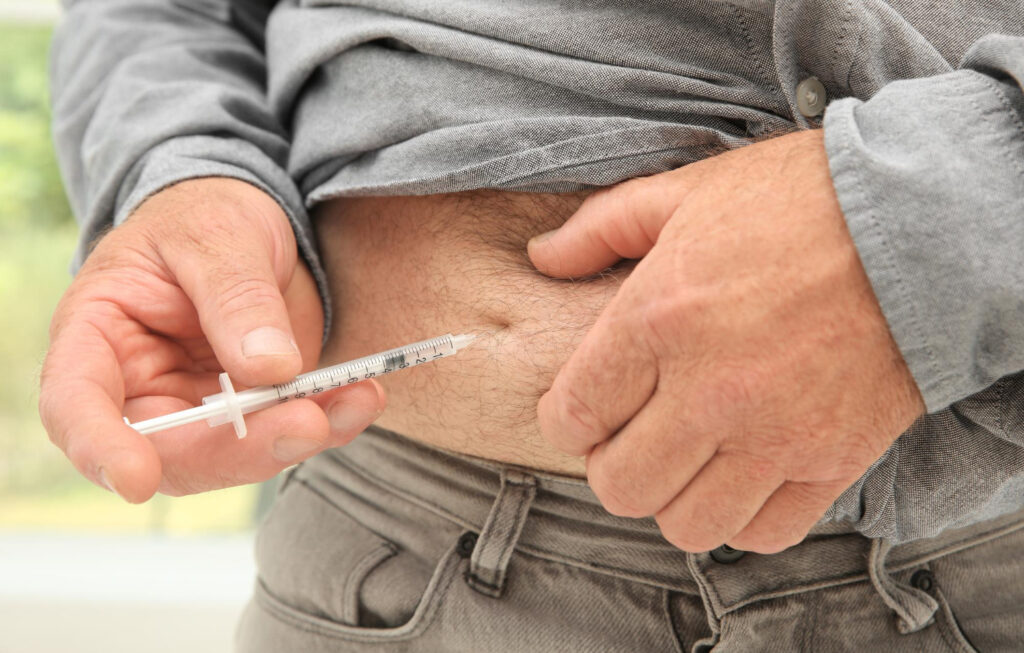 Ein Mann spritzt sich einen GLP-1-Rezeptor-Agonisten in den Bauch.