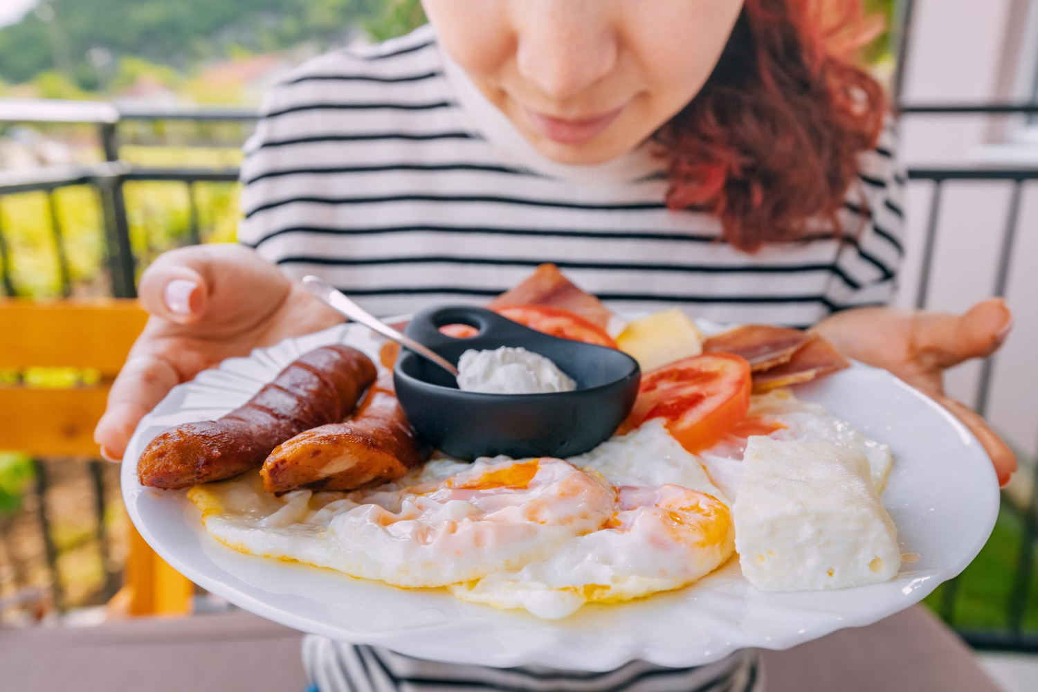 Eine Frau hält einen Teller mit englischem Frühstück voller pflanzlicher und tierischer Proteine für den täglichen Bedarf.