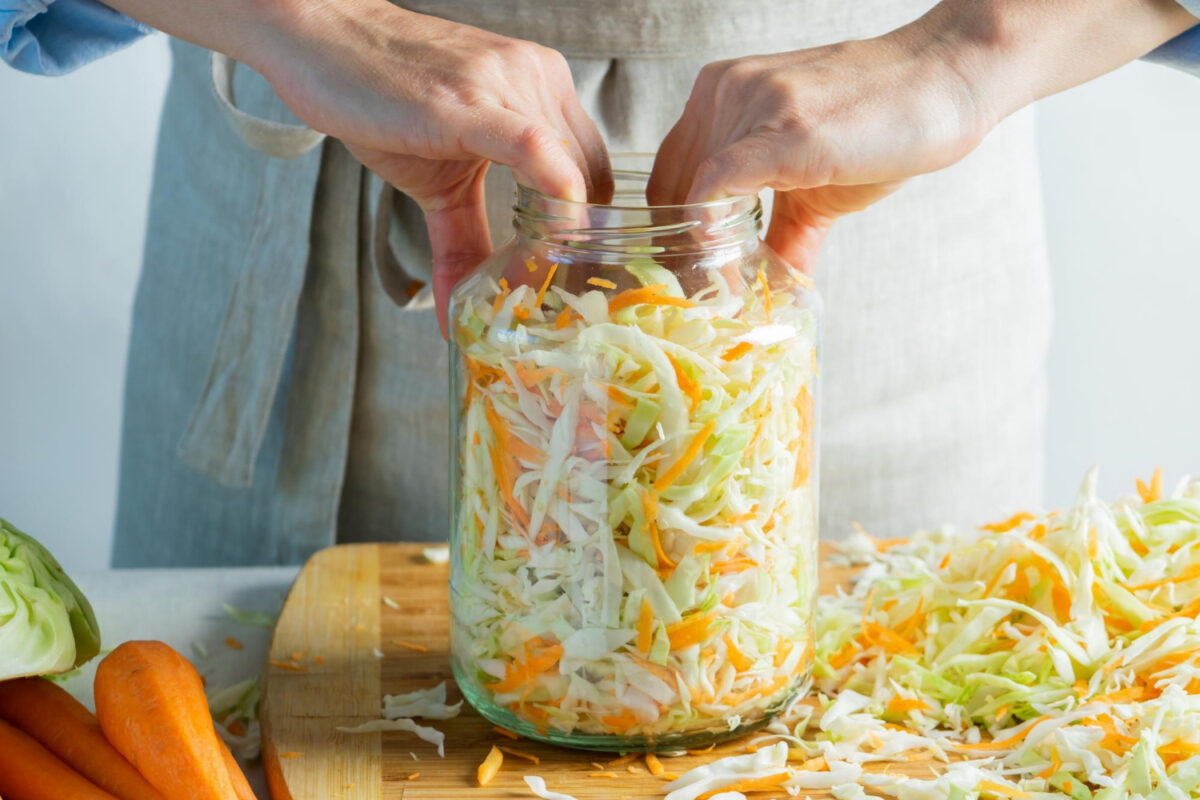 Eine Person gibt Gemüse zur Fermentation und für Präbiotika und Probiotika in ein Einmachglas.