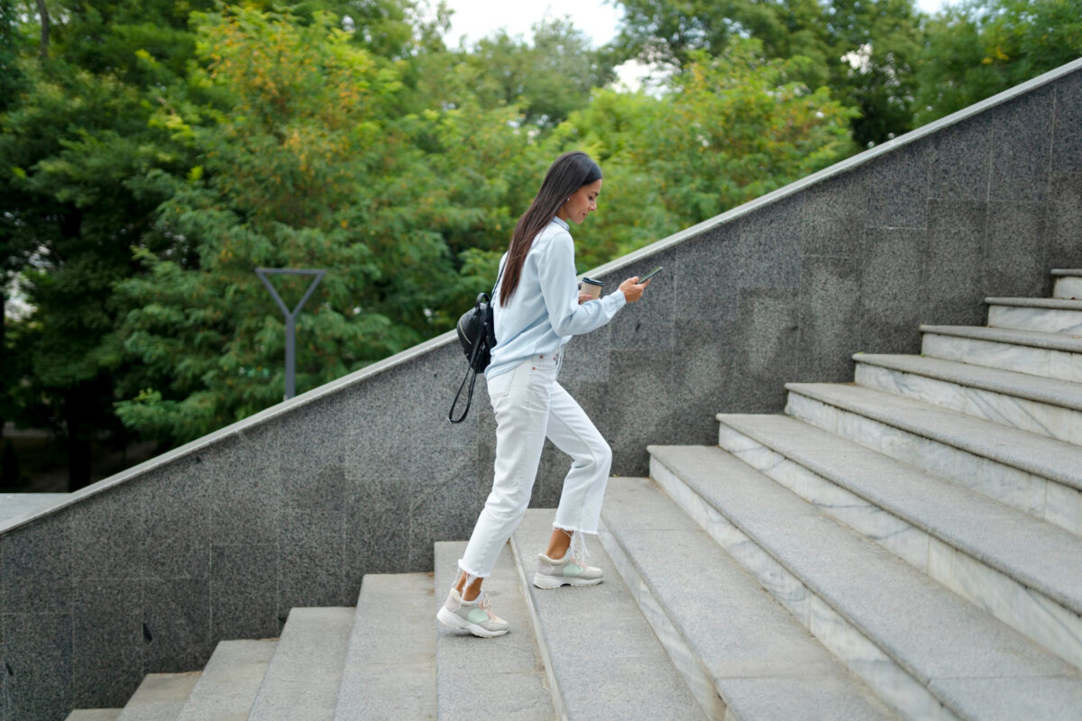 Eine Frau geht eine Treppe hinauf und bleibt aktiv. Sinnbild für Gewicht halten nach dem Abnehmen.