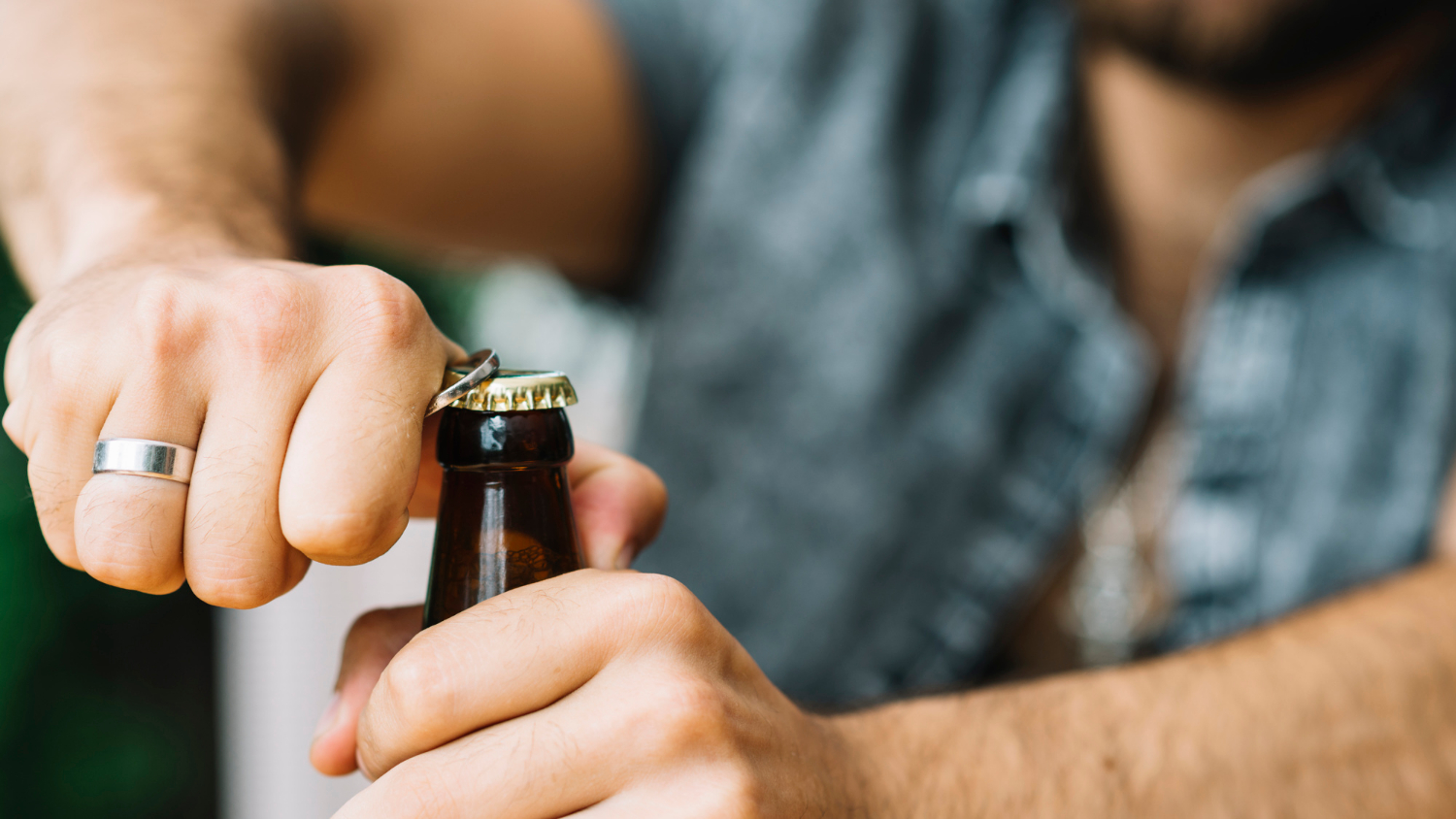 Ein Mann öffnet eine Bierflasche. Sinnbild für die Wirkung von Alkohol.
