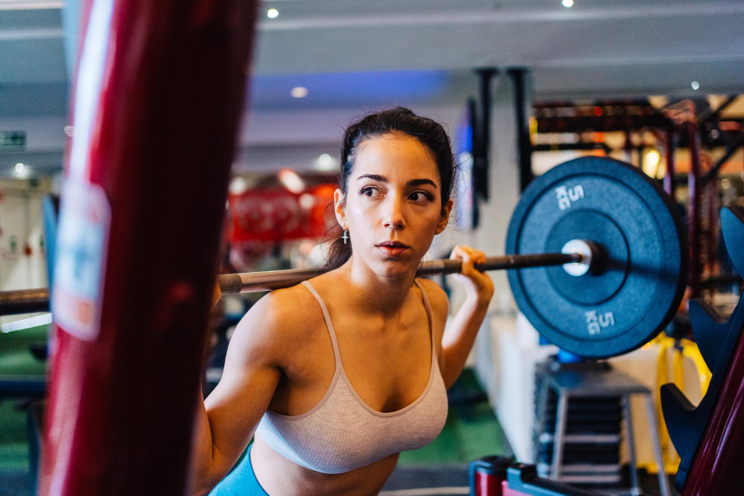 Eine Frau hebt eine Langhantel im Fitnessstudio. Sinnbild für die Vorteile von Krafttraining.