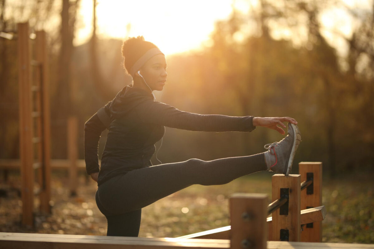 Eine Frau dehnt sich vor der untergehenden Sonne beim Sport am Abend zu ihrer Trainingszeit.